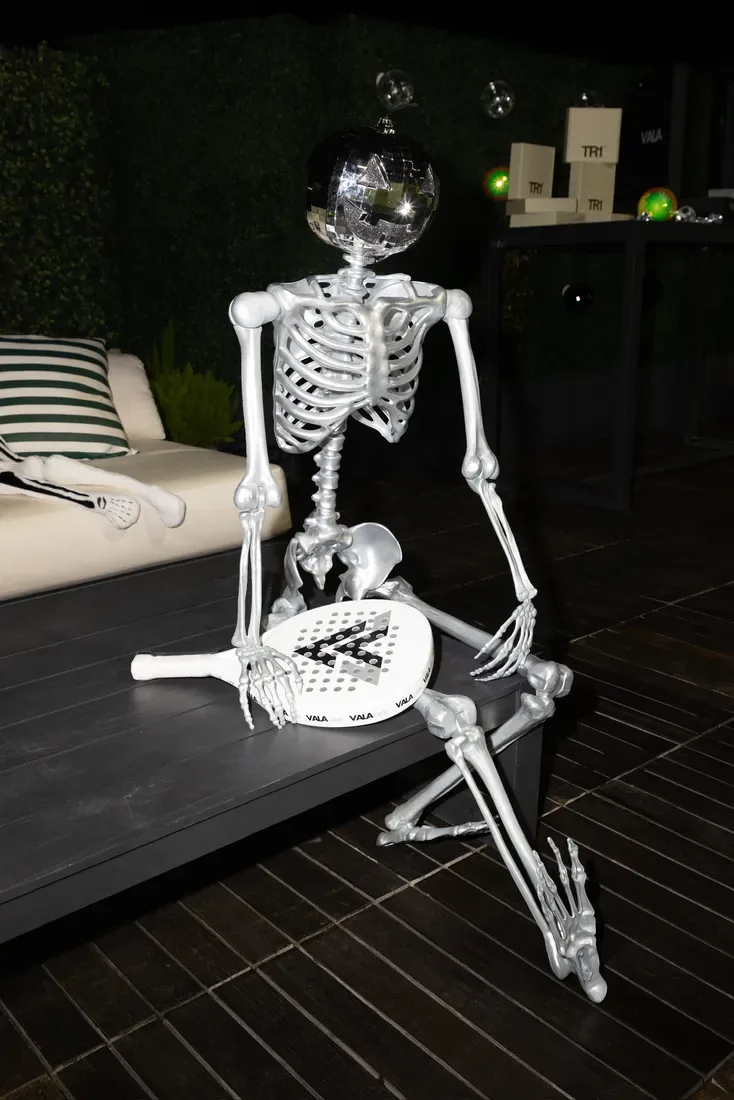 A silver skeleton holding a padel racket in the Halloween lounge