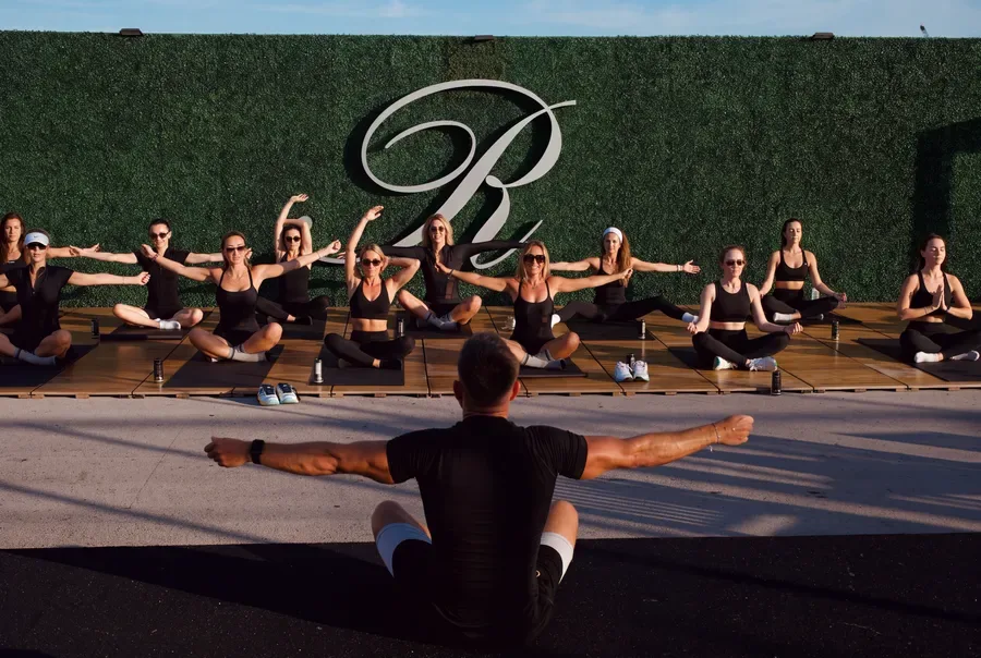 An outdoor Pilates class extending their arms with the instructor